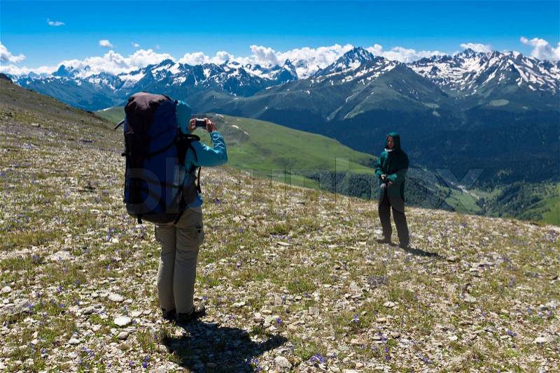 Amateur tourist girl making photo of her friend on mountain landscape, stock photo
