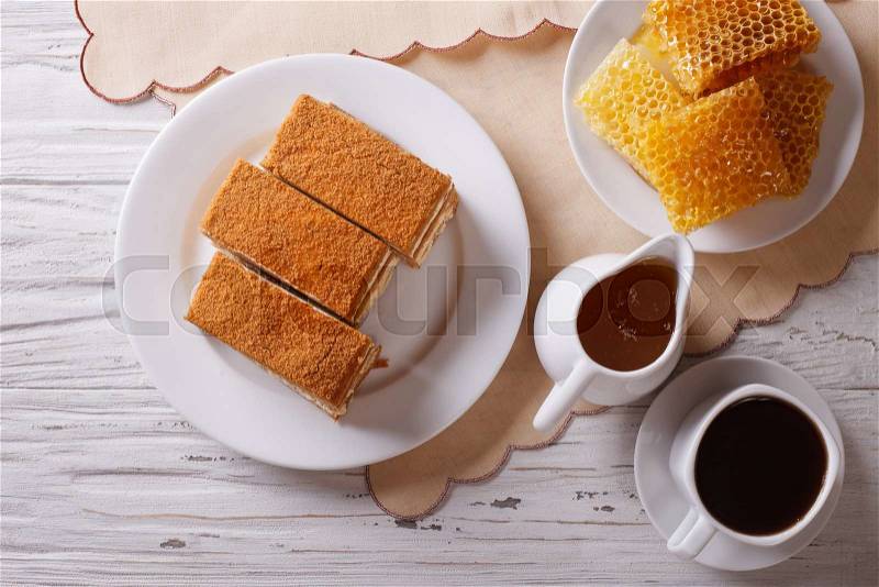 Sliced honey cake on a plate, coffee, and a honeycomb. Horizontal top view , stock photo