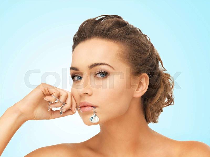 Beautiful woman holding shiny diamond necklace in mouth, stock photo