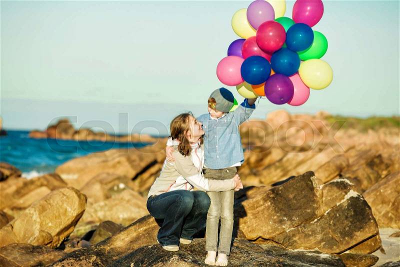 Happy mother and son having quality family time on the beach playing with balloons on summer holidays. Lifestyle, vacation, happiness concept, stock photo