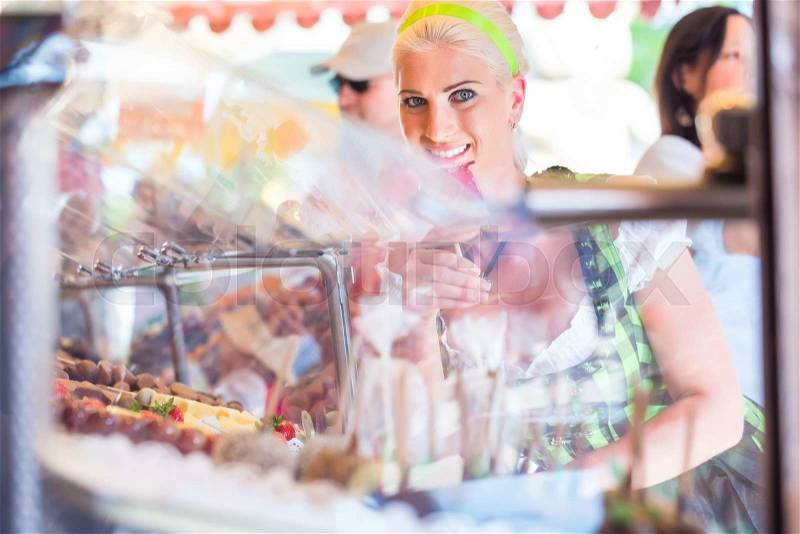 Woman eating candy apple at Oktoberfest wearing Dirndl , stock photo