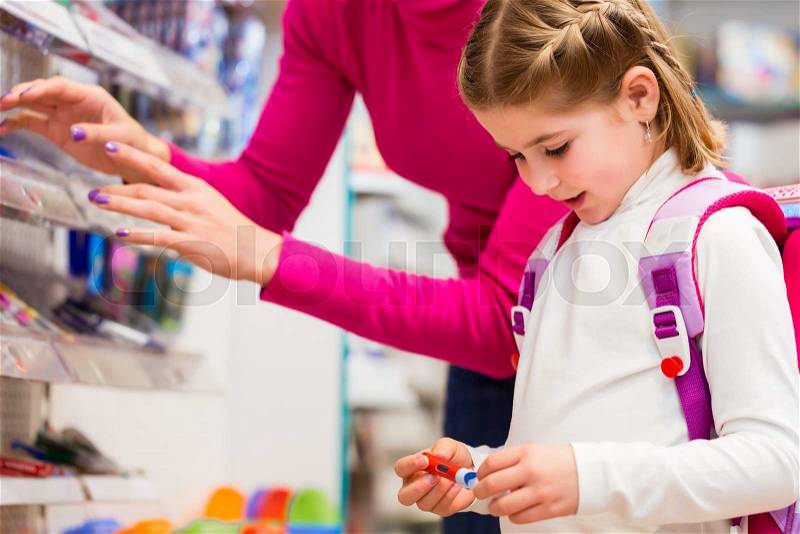 Family buying school supplies in stationery store, little girl looking at a fountain pen, stock photo