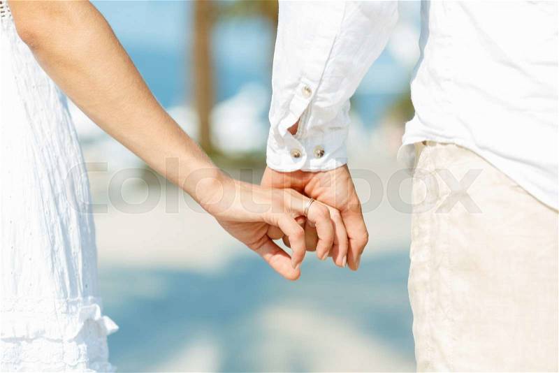 Concept shoot of friendship and love of man and woman: two hands over waterfront, stock photo