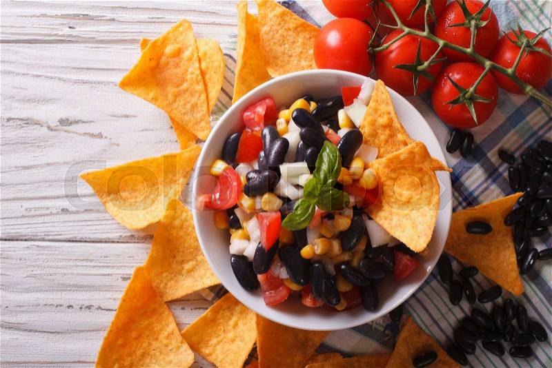 Mexican salsa with beans in a bowl and corn chips nachos on the table close-up. horizontal view from above , stock photo