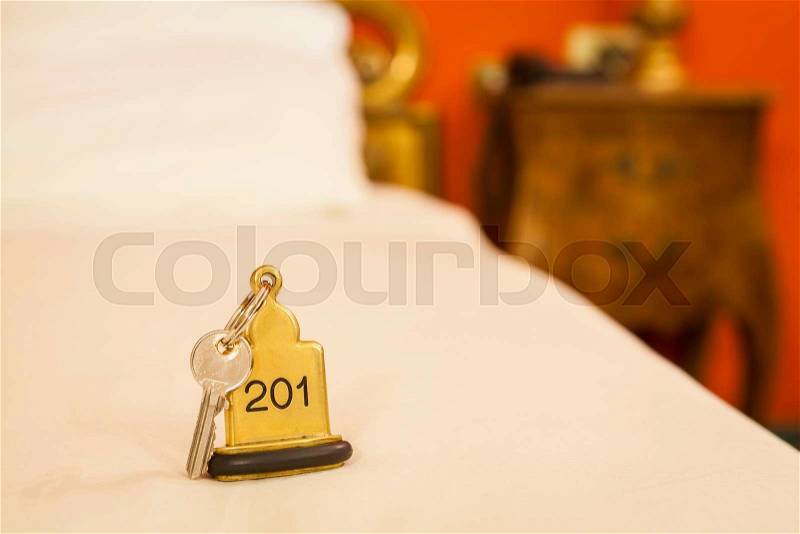 Hotel Room Key lying on Bed with keyring golden, stock photo