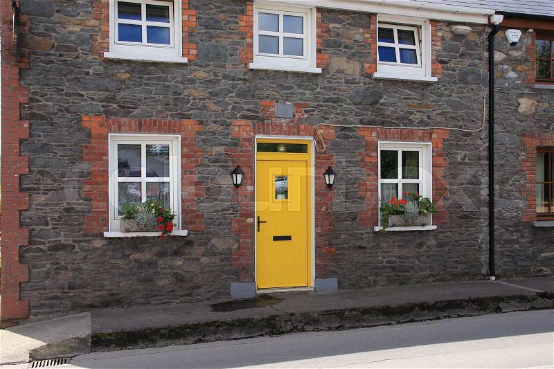 Terraced house with striking yellow painted front door in the residential area in Dingle, county Kerry, in Ireland in the summer, stock photo