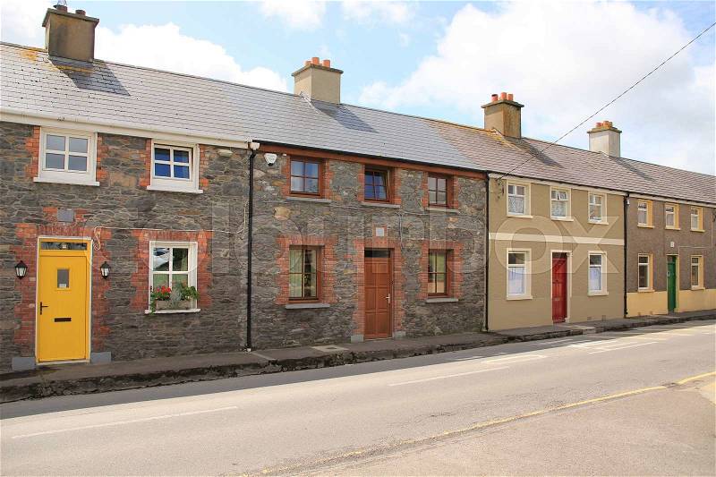 Terraced houses with striking front doors in the colour yellow, brown, red or green in the residential area in Dingle, county Kerry, in Ireland in the summer, stock photo