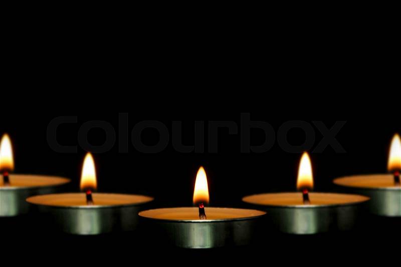 Some candles are against the dark black background, stock photo