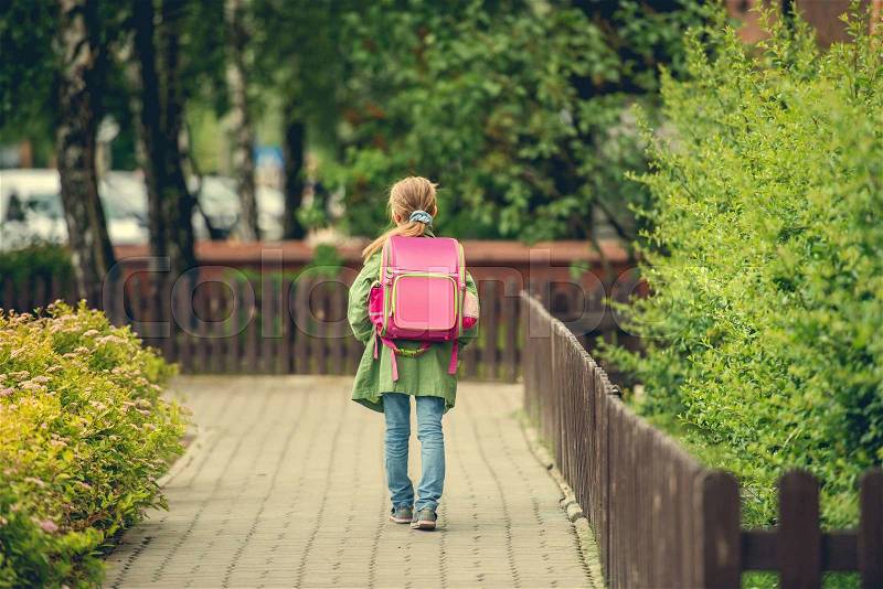 Little girl with a backpack going to school. back view, stock photo