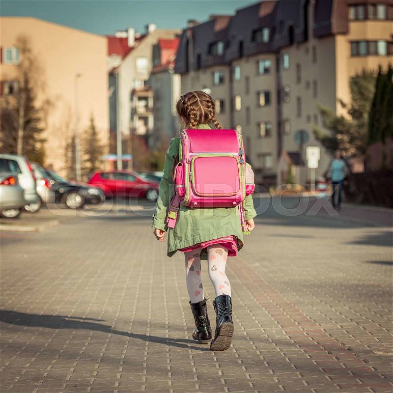 Little girl with a backpack going to school, stock photo