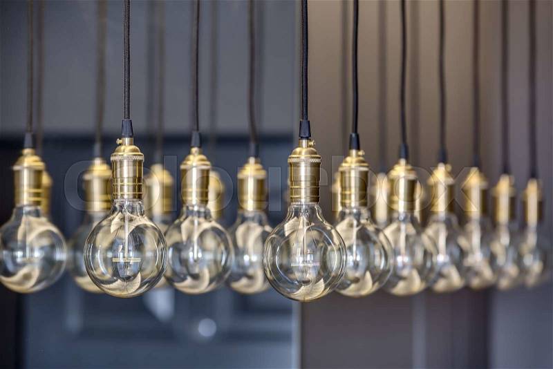 Edison lamps suspended from the ceiling in a regular geometric sequence. One lamp in focus. The rest of the optical out of focus. , stock photo