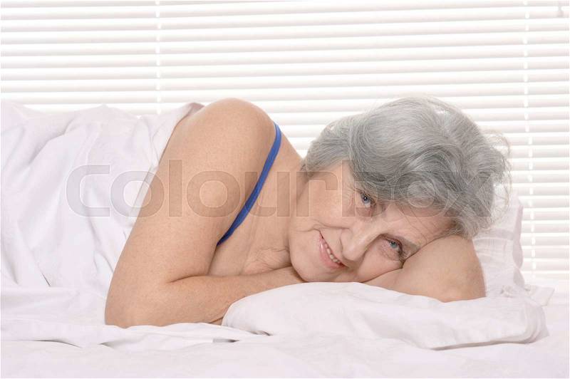 Happy senior woman resting in a bedroom, stock photo