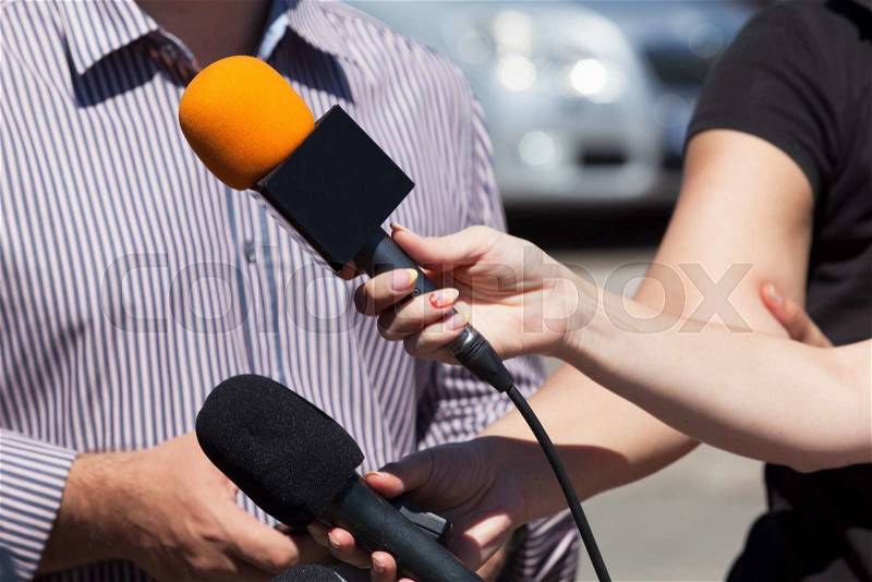 Reporters taking interview at press conference, stock photo