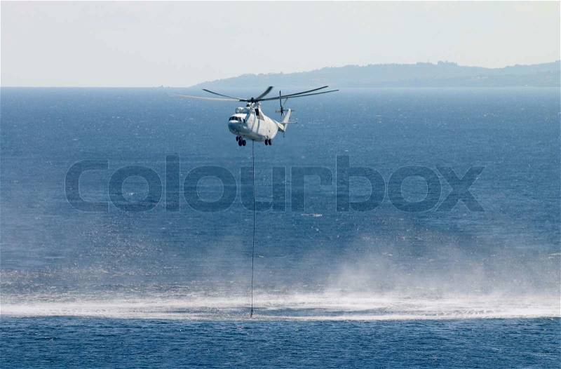 Fire fighting helicopter pick up water from sea, stock photo