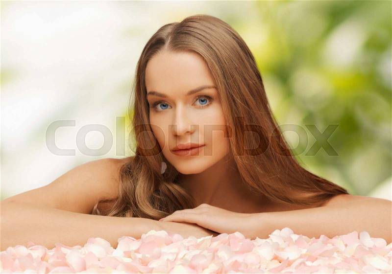 Health and beauty concept - beautiful woman with rose petals and long hair, stock photo