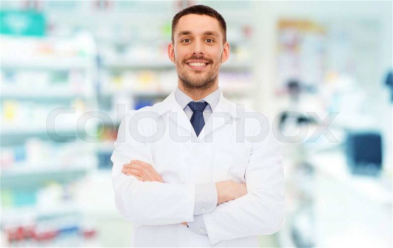 Medicine, pharmacy, people, health care and pharmacology concept - smiling male pharmacist in white coat over drugstore background, stock photo
