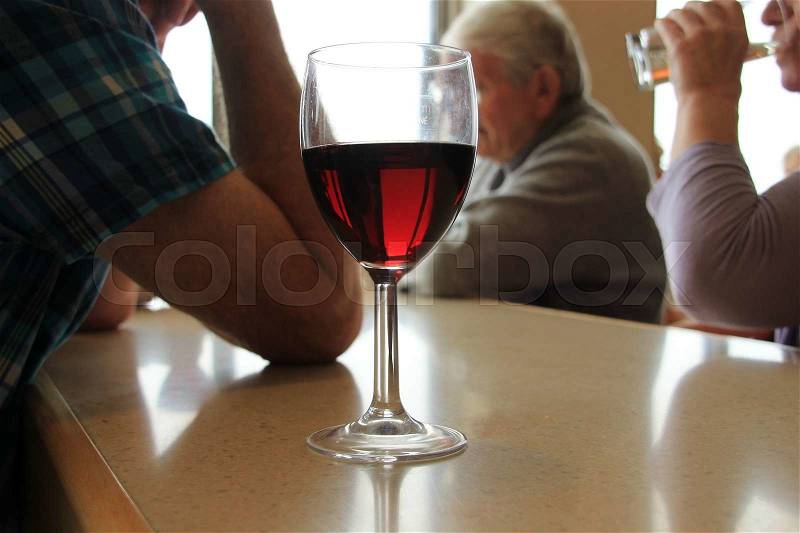 The lady drinks her glass empty and on the table stands a glass of red wine for the man in the bistro in the summer, stock photo