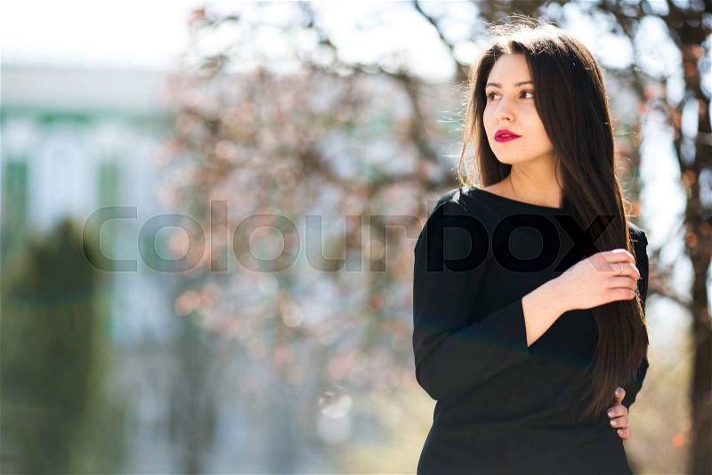 Young beautiful girl posing in a black leather jacket in the park, stock photo