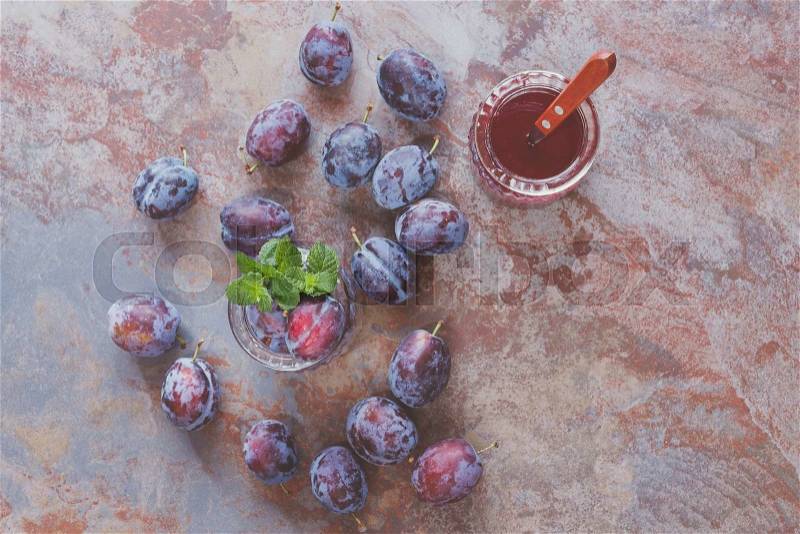 Plums and plum juice. Fresh scattered plums and plum juice in jar on rustic background. Vintage style, top view, stock photo