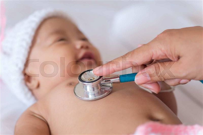 Pediatric doctor exams newborn baby girl with stethoscope in hospital, stock photo
