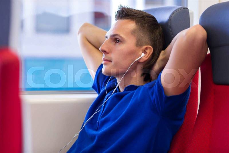 Young man talking on the phone and listen music traveling by train, stock photo