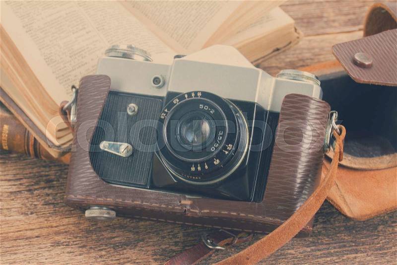 Retro photo camera with books on wooden background, retro toned, stock photo