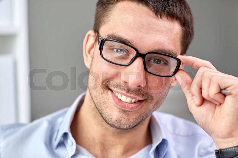 Business, people and work concept - portrait of smiling businessman in eyeglasses face in office, stock photo