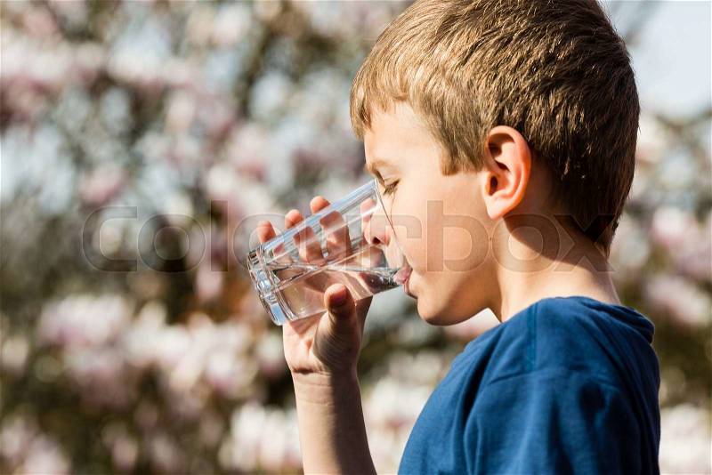 Young boy drinking from glass of fresh water. Ideal for environmental protection or future generations concept, stock photo