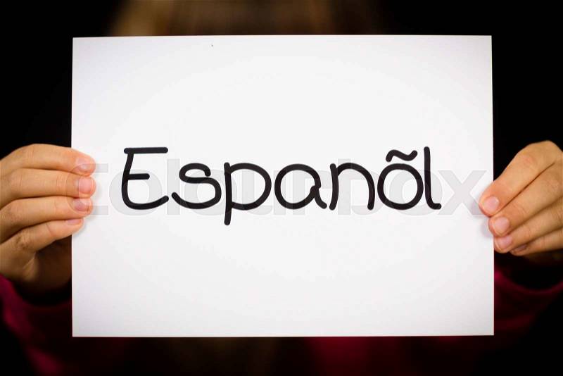 Studio shot of child holding a sign with Spanish word Espanol - Spanish in English, stock photo