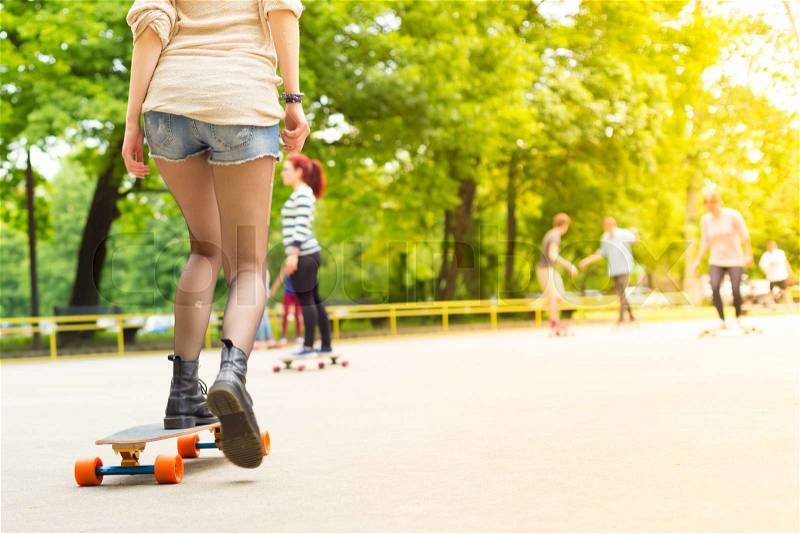 Teenage girl wearing black boots and stockings practicing long board riding outdoors in skateboarding park. Active urban life. Urban subculture, stock photo