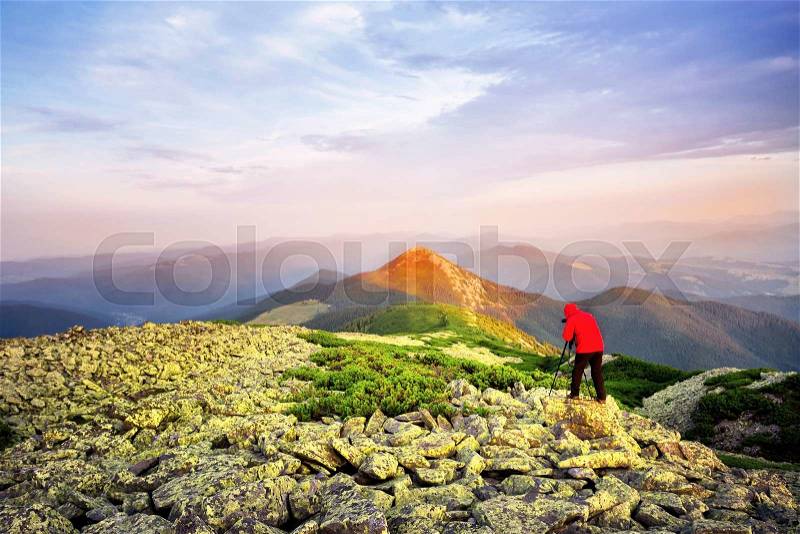 Photographer taking pictures on a hill mountaintop lit red, stock photo