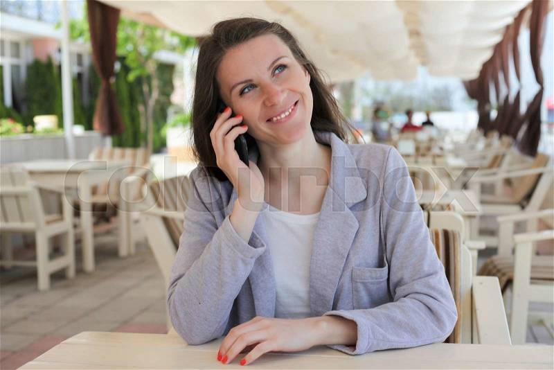 Girl using smart phone in a restaurant terrace with an unfocused background, stock photo