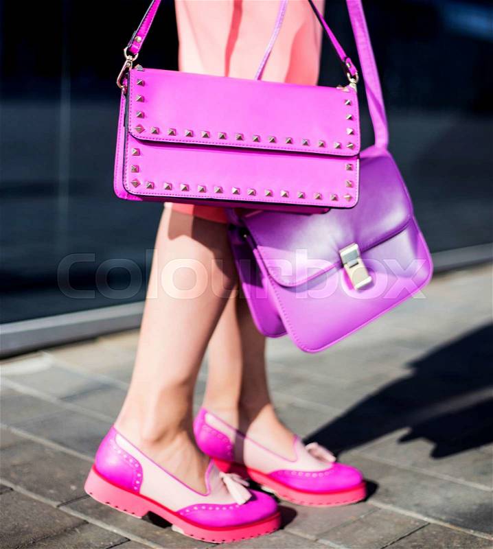 Fashion model with clutch in pink dress and shoes poses outdoors, stock photo