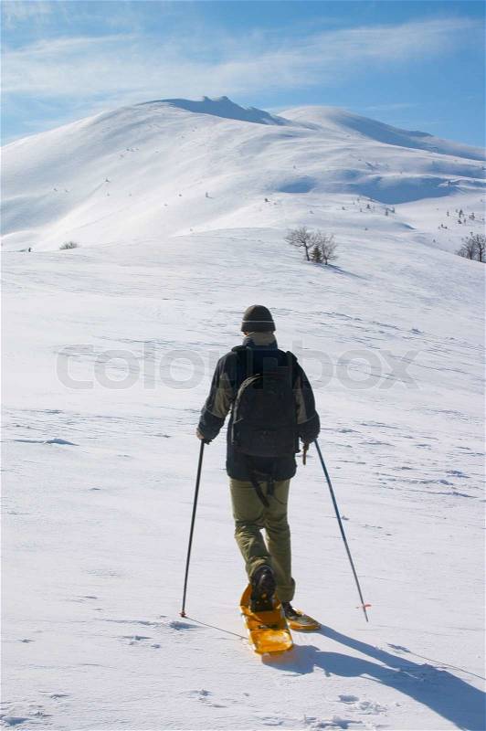 Backpacker in snow shoes going to snow mountain, stock photo
