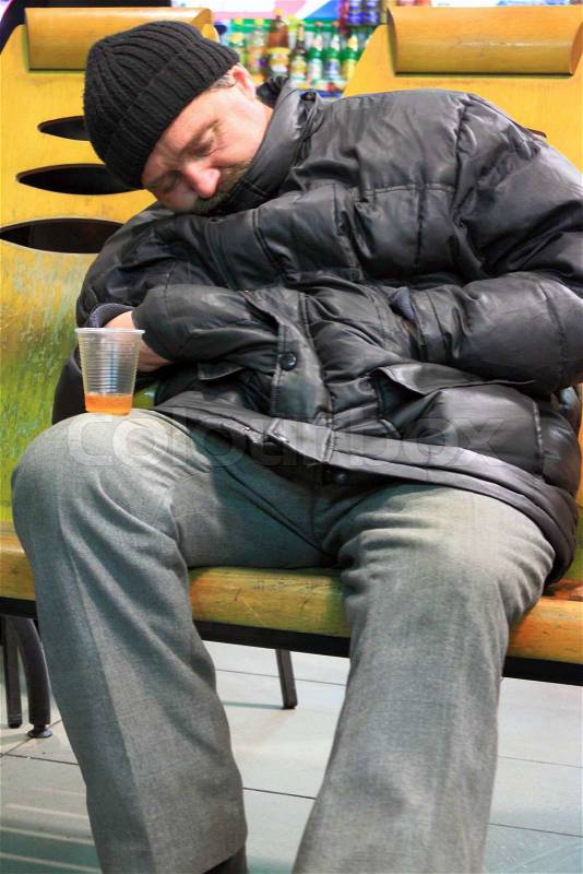 Homeless Drunk man sleeping on a bench with a glass of alcohol, stock photo