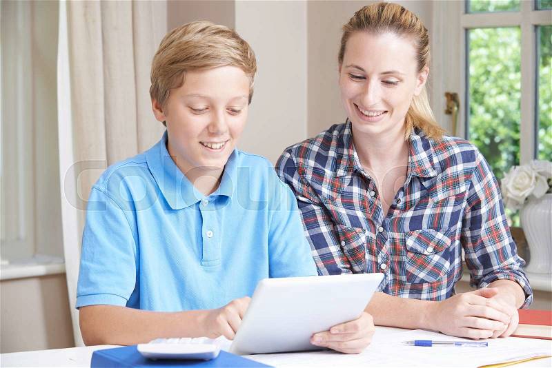 Female Home Tutor Helping Boy With Studies Using Digital Tablet, stock photo
