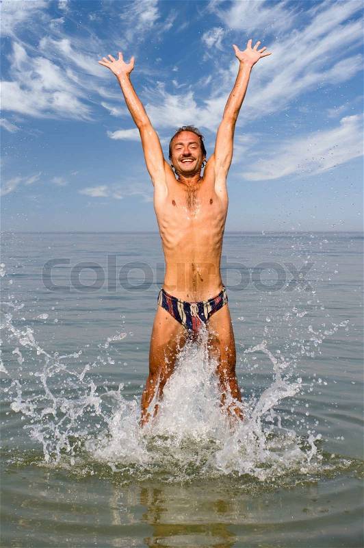 Happy man jump in sea with splashes, stock photo