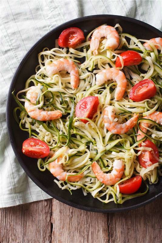 Zucchini pasta with shrimp and tomato on a plate close-up. Vertical top view\, stock photo
