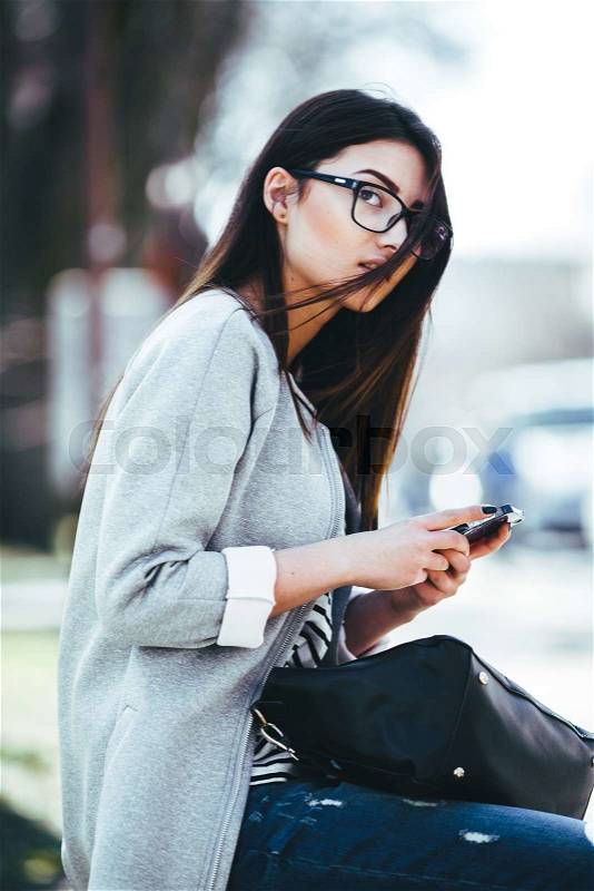 Charming beautiful fashion model in the glasses, sits, stock photo