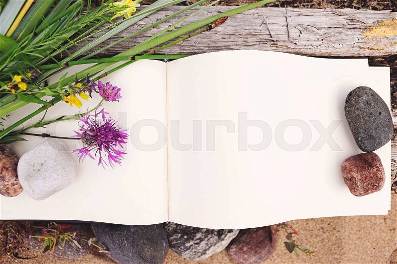 Sketch book, country flowers and stones on weathered wood, mock up, stock photo