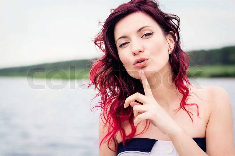Secret woman. Female showing hand silence sign, natural outdoor background, stock photo