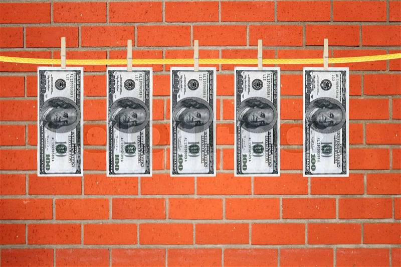 Dollars laundering and dry after wash hang on clothespins over orange brick wall, stock photo