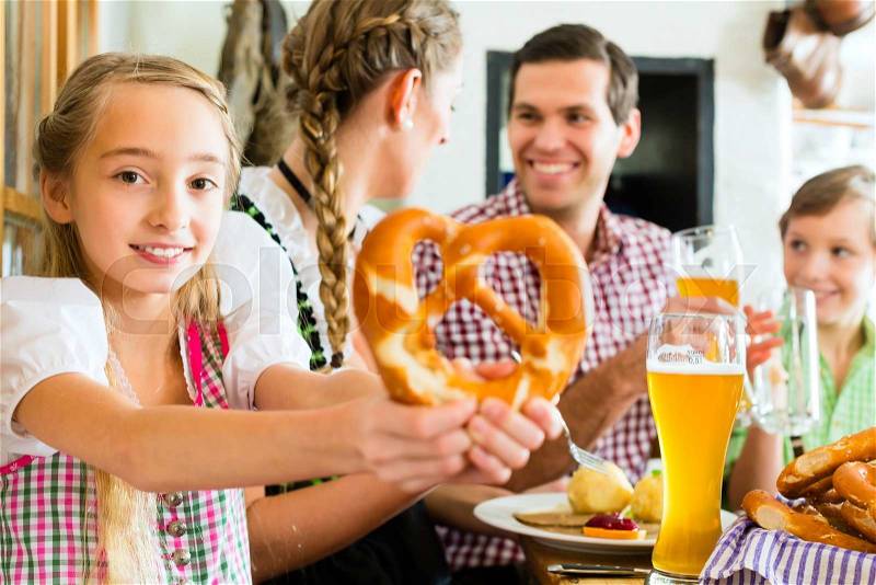 Bavarian girl wearing dirndl and eating with family in traditional restaurant , stock photo