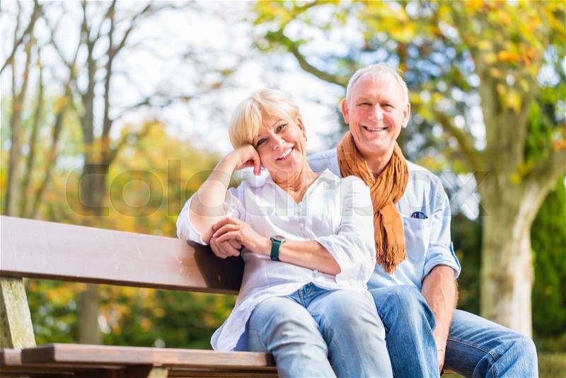 Senior woman and man sitting on part bench in fall , stock photo