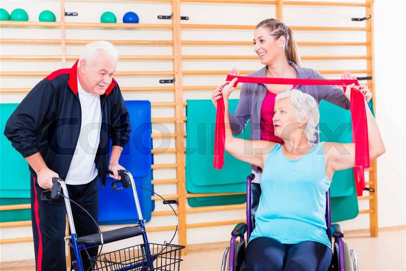 Seniors in physical rehabilitation therapy with trainer, stock photo