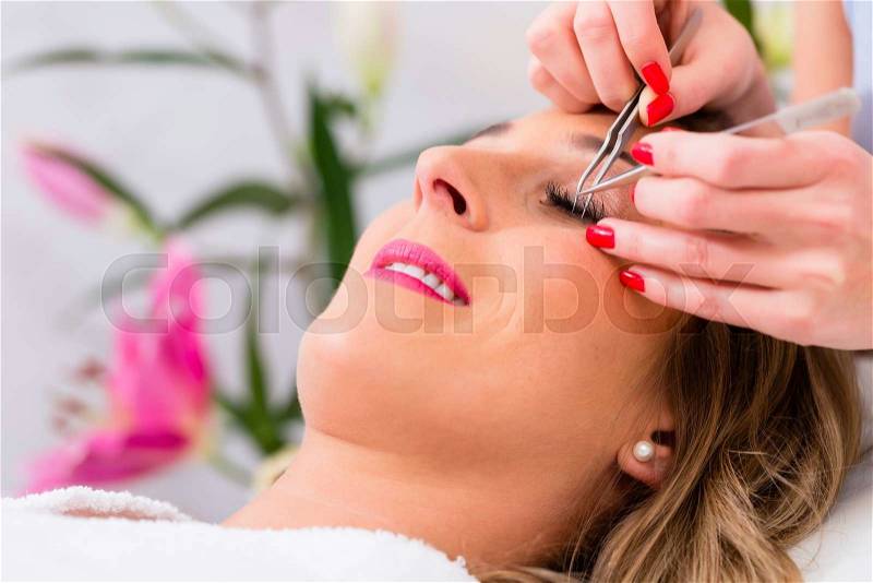 Woman receiving false eye lashes in beauty studio, stock photo