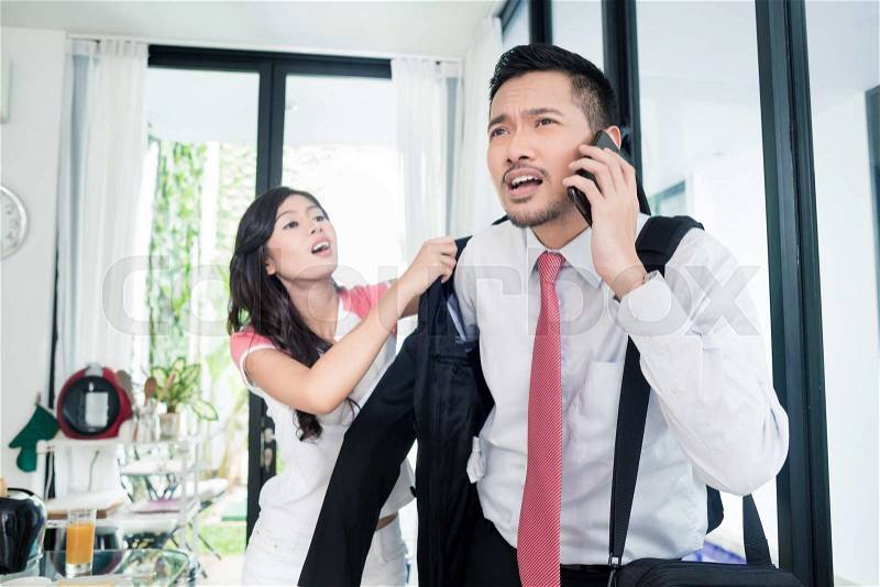 Wife helping man being late for work in jacket, the couple is in a hurry, stock photo