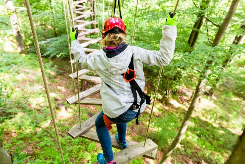 Girl seen from above climbing in high rope course, stock photo
