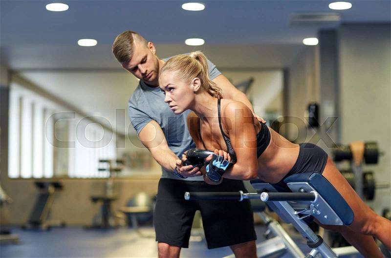 Sport, training, fitness, lifestyle and people concept - young woman with personal trainer flexing back and abdominal muscles on bench in gym, stock photo