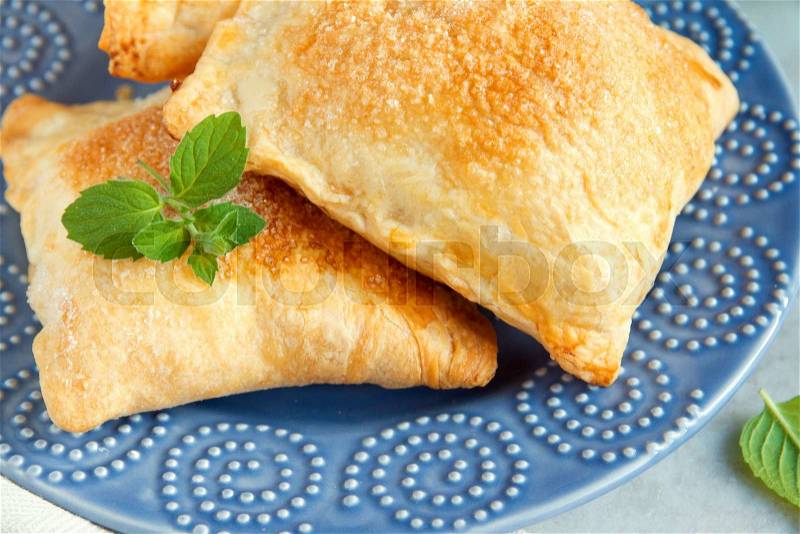 Puff pastry with sugar and mint close up on blue plate, stock photo